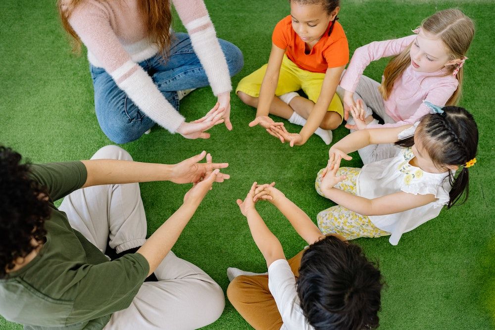 assistantes maternelle assissent en cercle avec des enfants