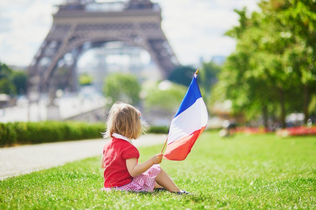Une petite fille avec un drapeau français devant la tour Eiffel