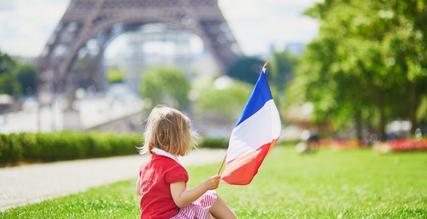 Une petite fille avec un drapeau français devant la tour Eiffel